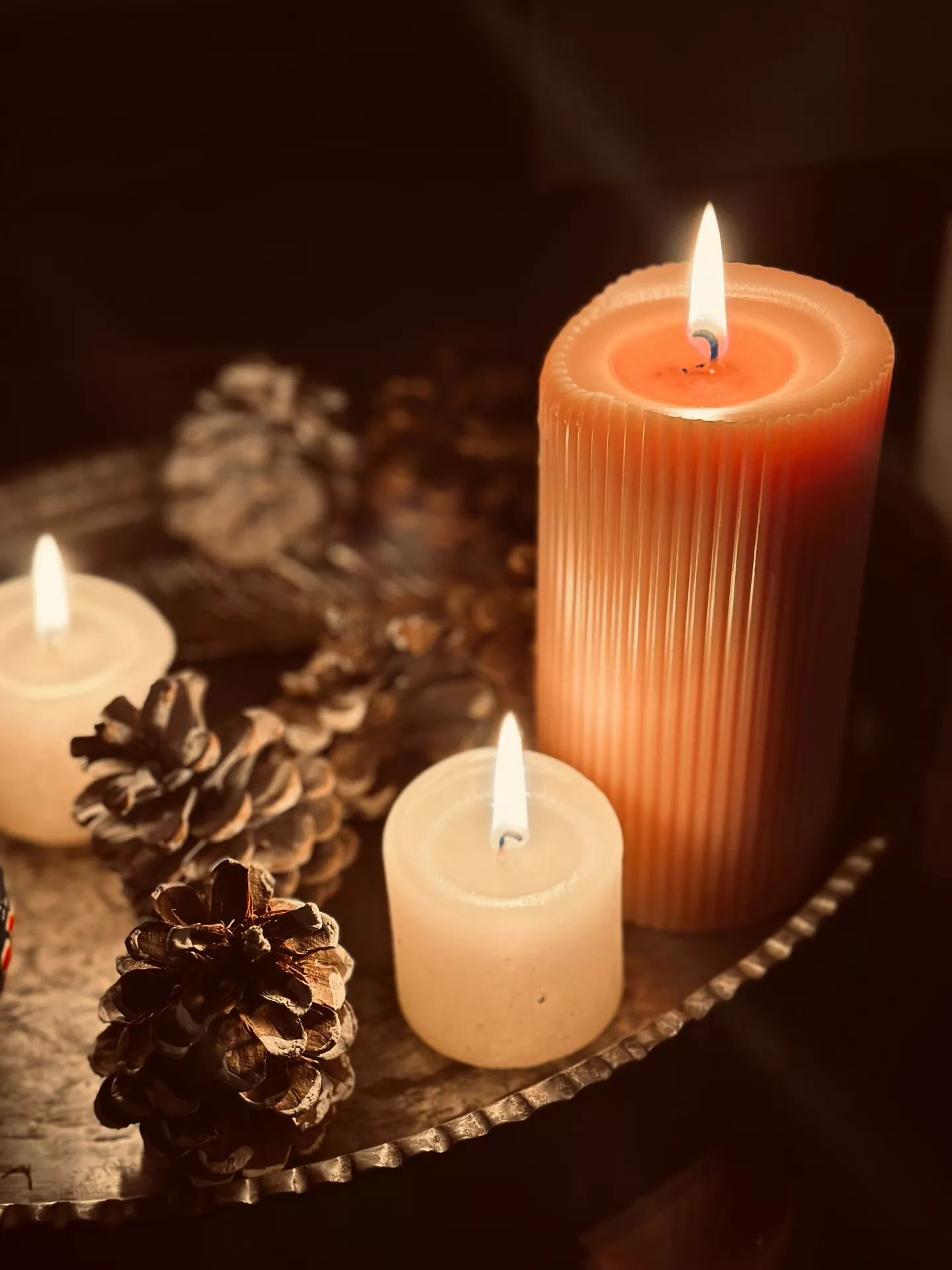 Fall tray decor ideas showcasing Pine Cones & Candles on a rustic metal tray with glowing pillar and votive candles, natural pine cones, and warm ambient lighting to create a cozy and inviting autumn atmosphere.