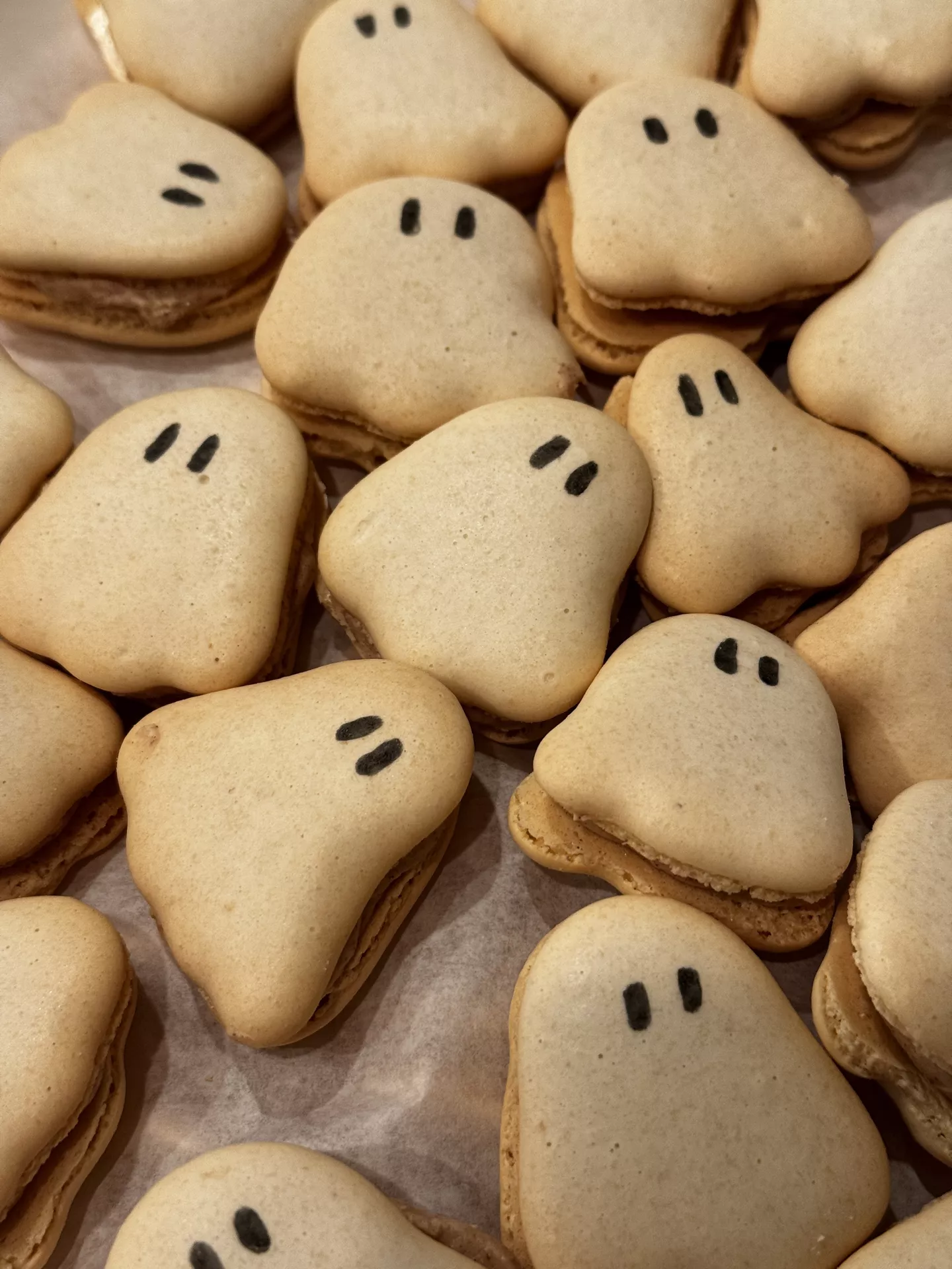 Halloween Party Food Ideas featuring adorable ghost macarons with simple black eyes, arranged in a tray to create a fun and spooky dessert that is perfect for Halloween parties and festive sweet tables.