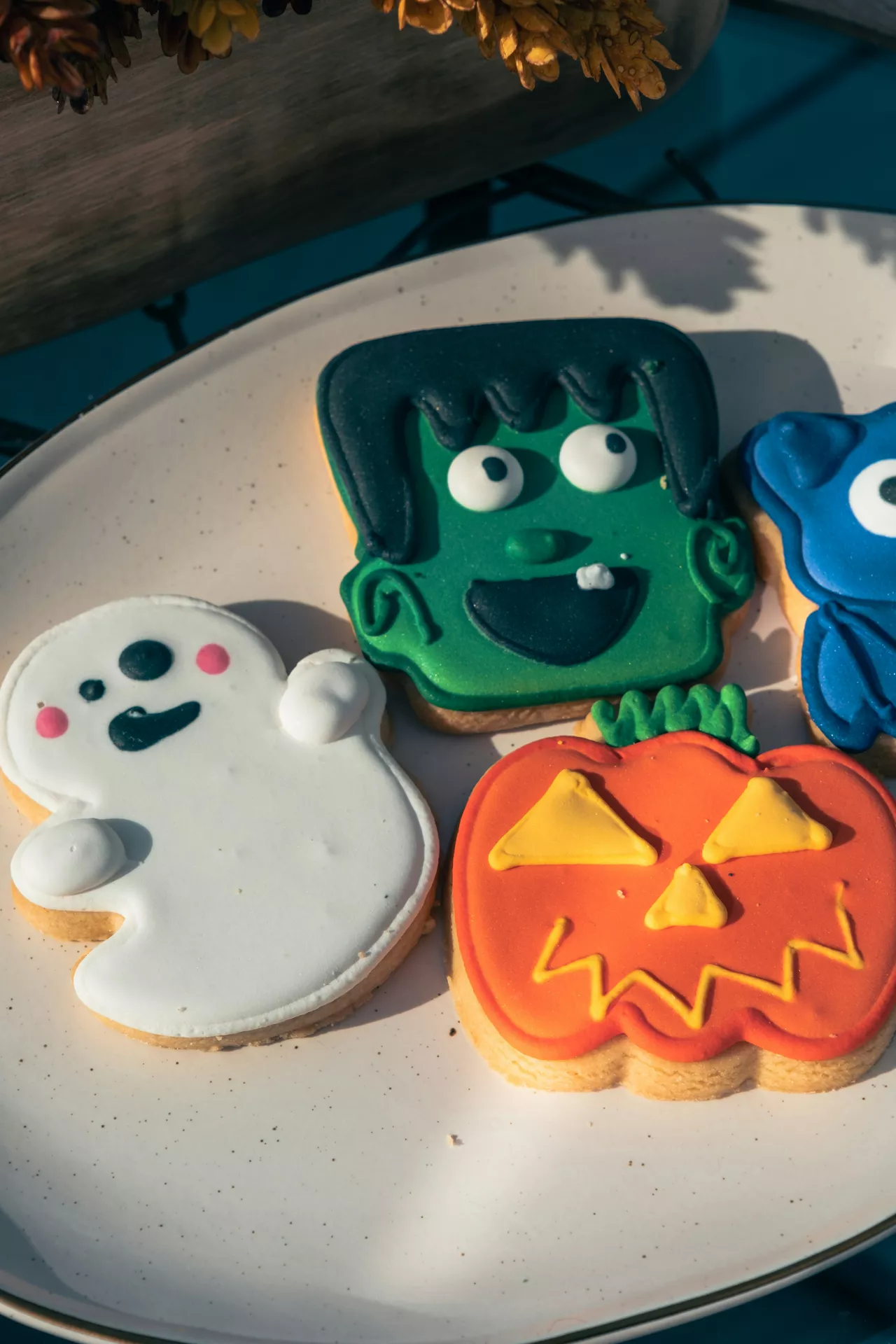 Halloween Party Food Ideas featuring colorful ghost, pumpkin and zombie cookies decorated with vibrant icing, arranged on a plate for a fun and festive Halloween dessert display.