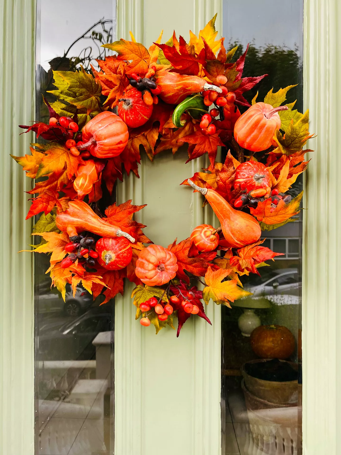 Fall decor wreaths featuring an Orange Wreath With Leaves, Pumpkins & Berries, beautifully arranged with vibrant autumn leaves, mini pumpkins, gourds, and bright red berries to create a warm and welcoming front door display.