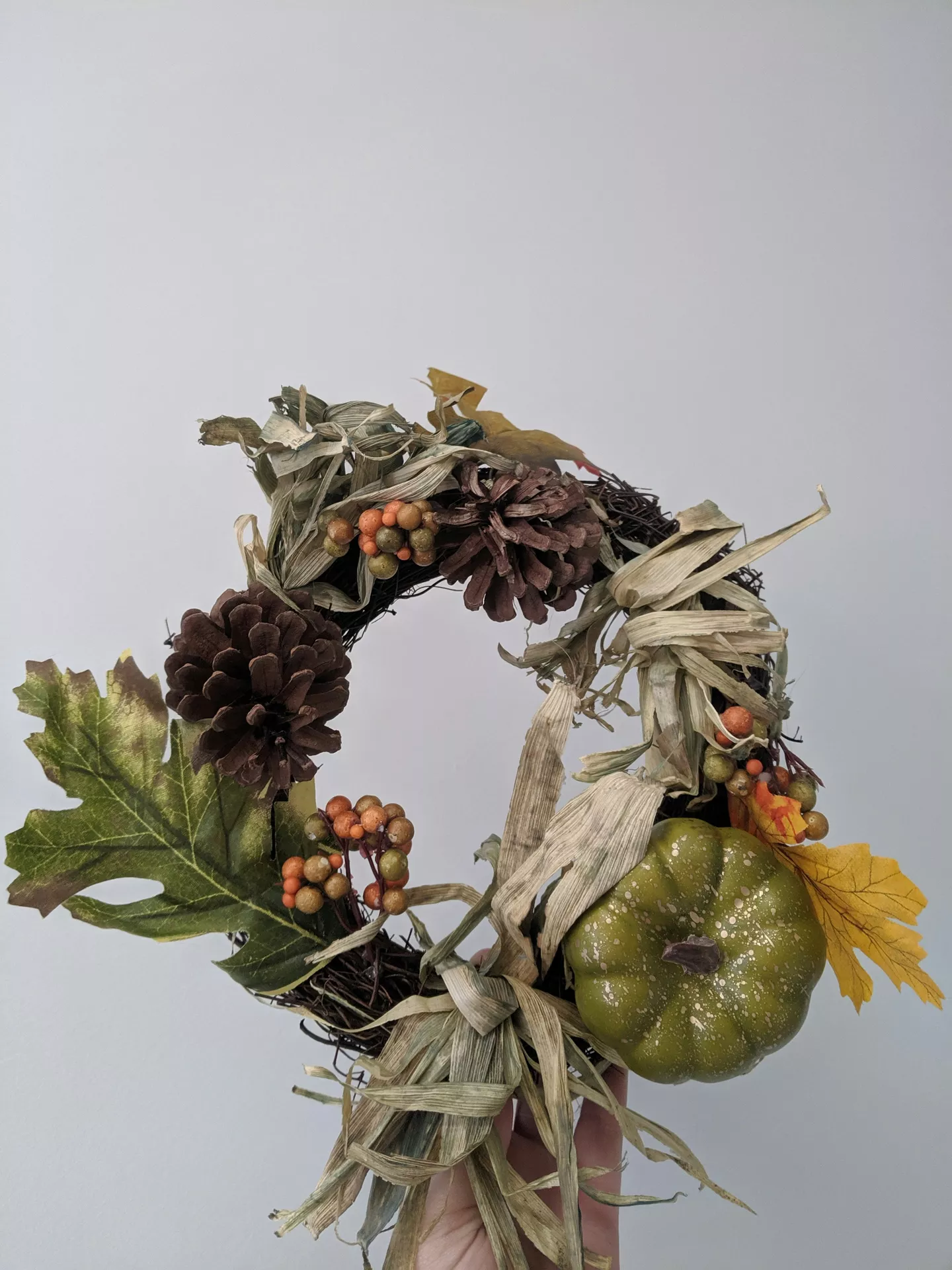 Fall decor wreaths featuring a Green Wreath With Pine Cones, Berries & Pumpkin, handcrafted with natural corn husks, pine cones, colorful berries, autumn leaves, and a green pumpkin for a charming rustic seasonal display.