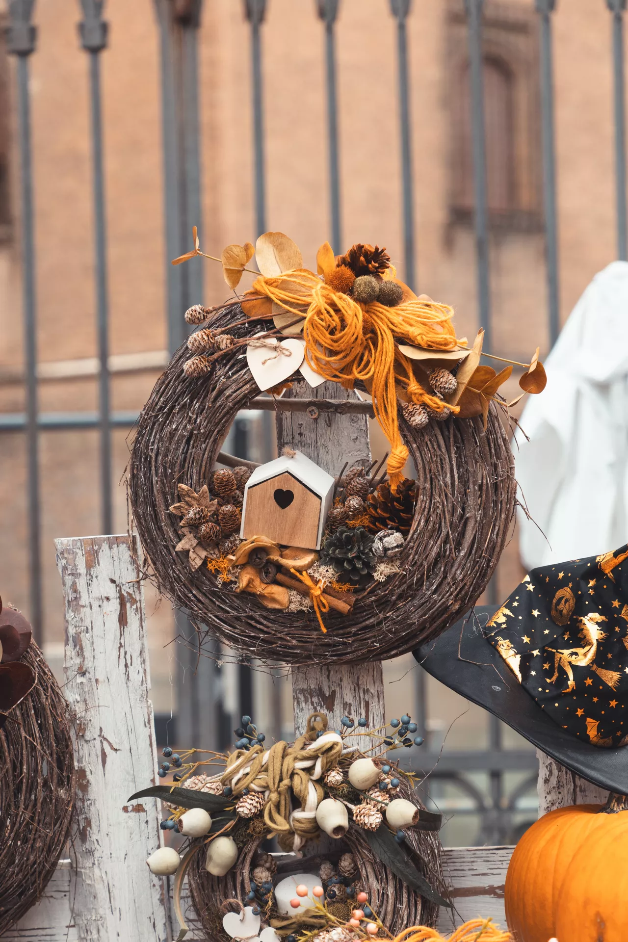 Fall decor wreaths featuring a rustic fall wreath with wooden birdhouses and pine cones, decorated with grapevine branches, dried botanicals, twine bows, and autumn accents for a charming farmhouse front porch display.