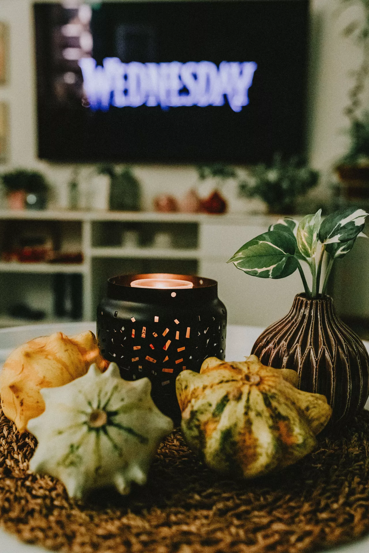 Fall living room decor ideas featuring a tea light and small pumpkins arranged on a woven tray with a decorative vase and greenery, creating a cozy autumn coffee table display.