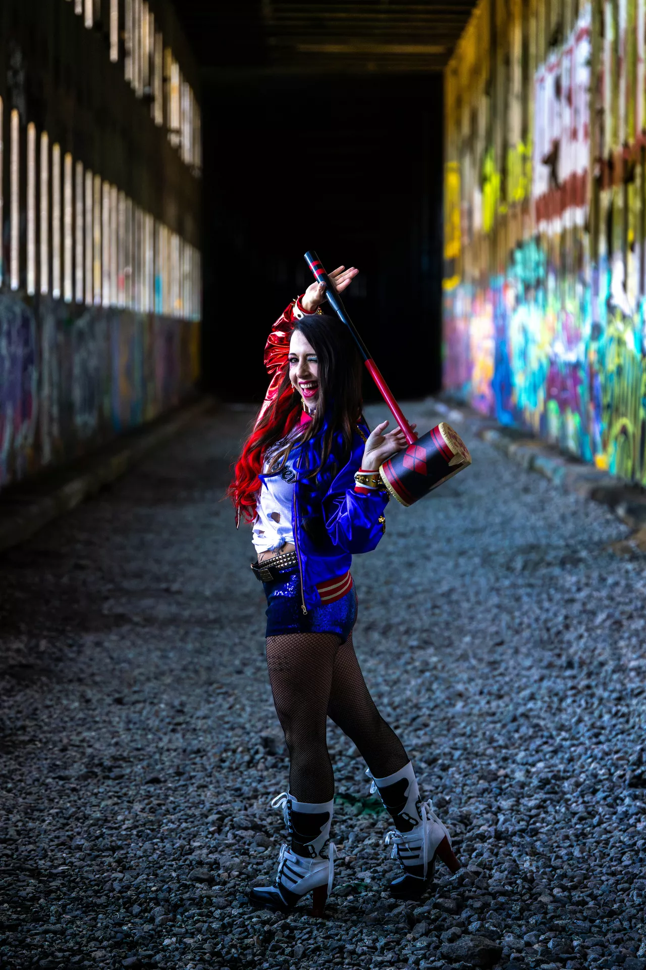 Halloween costume ideas featuring a harlequin-inspired woman in a red and blue outfit with fishnet tights, high-heeled boots, colorful hair, and a large red and black mallet.