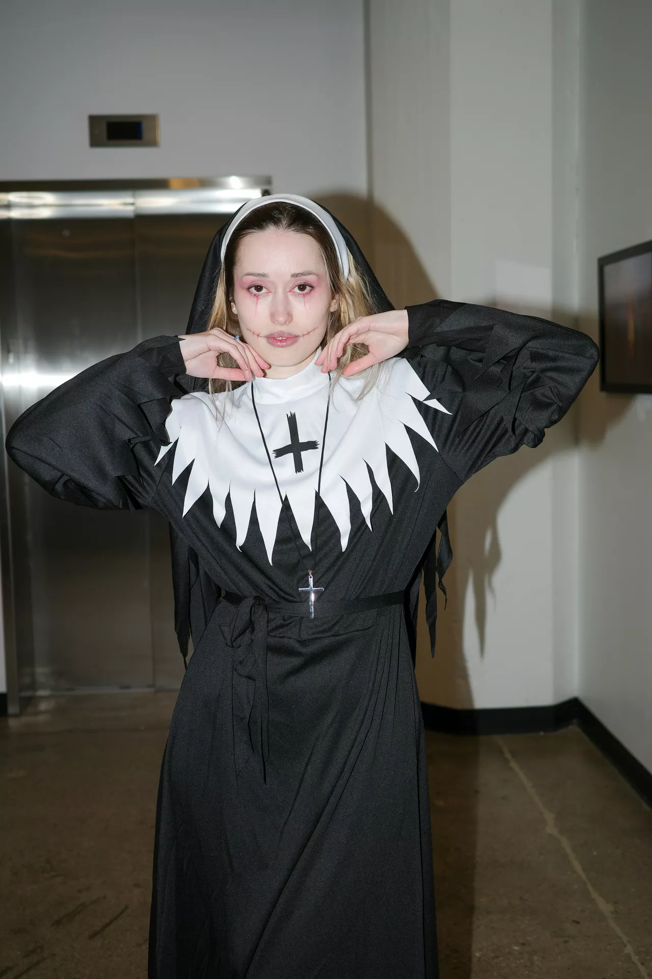 Halloween costume ideas featuring a spooky nun in a black and white habit with a cross necklace, red eye makeup, and eerie stitched-mouth face makeup.