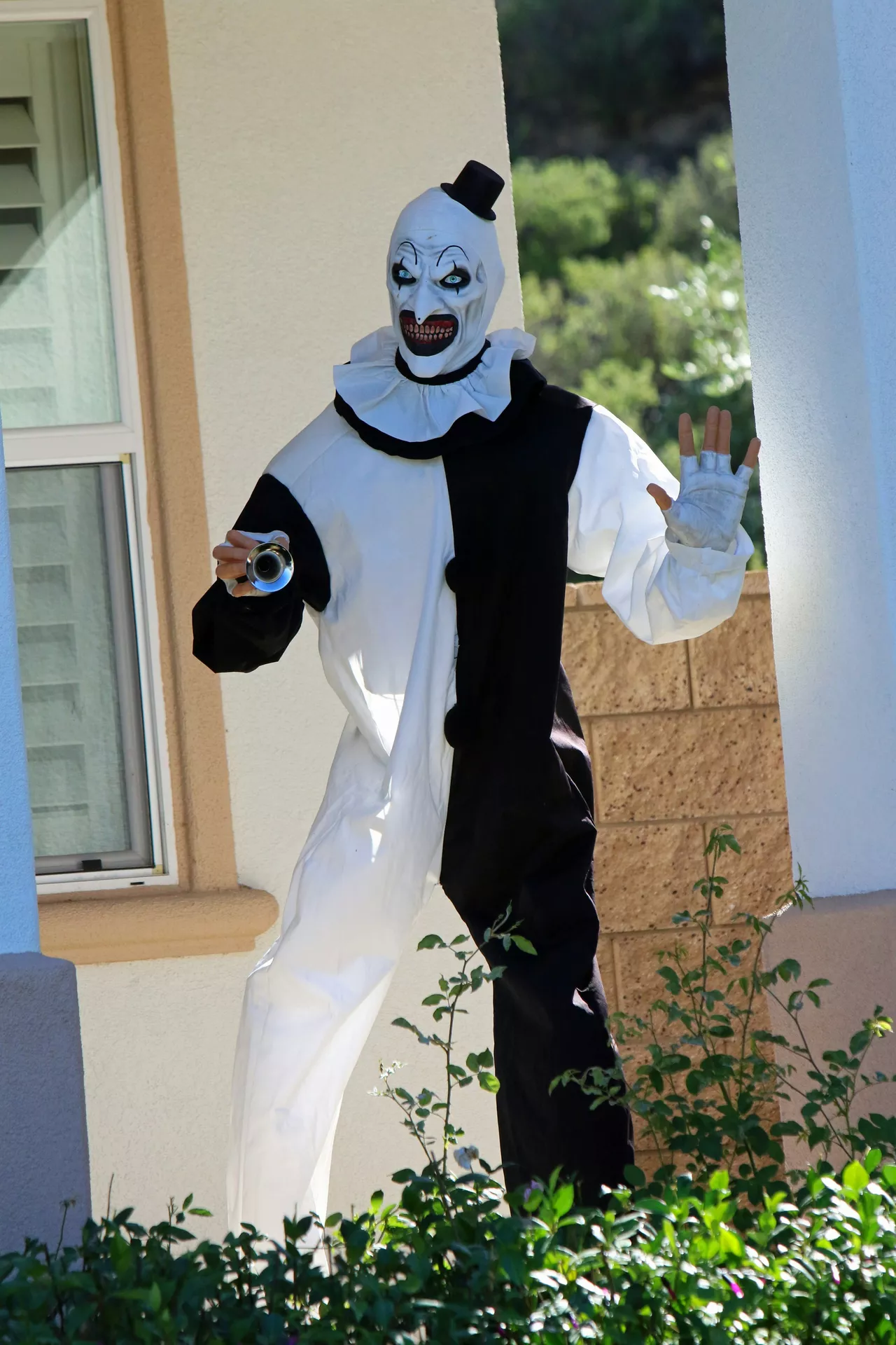 Halloween costume ideas featuring a Terrifier killer clown in a creepy black and white clown suit, sinister mask, tiny top hat, and dramatic ruffled collar.