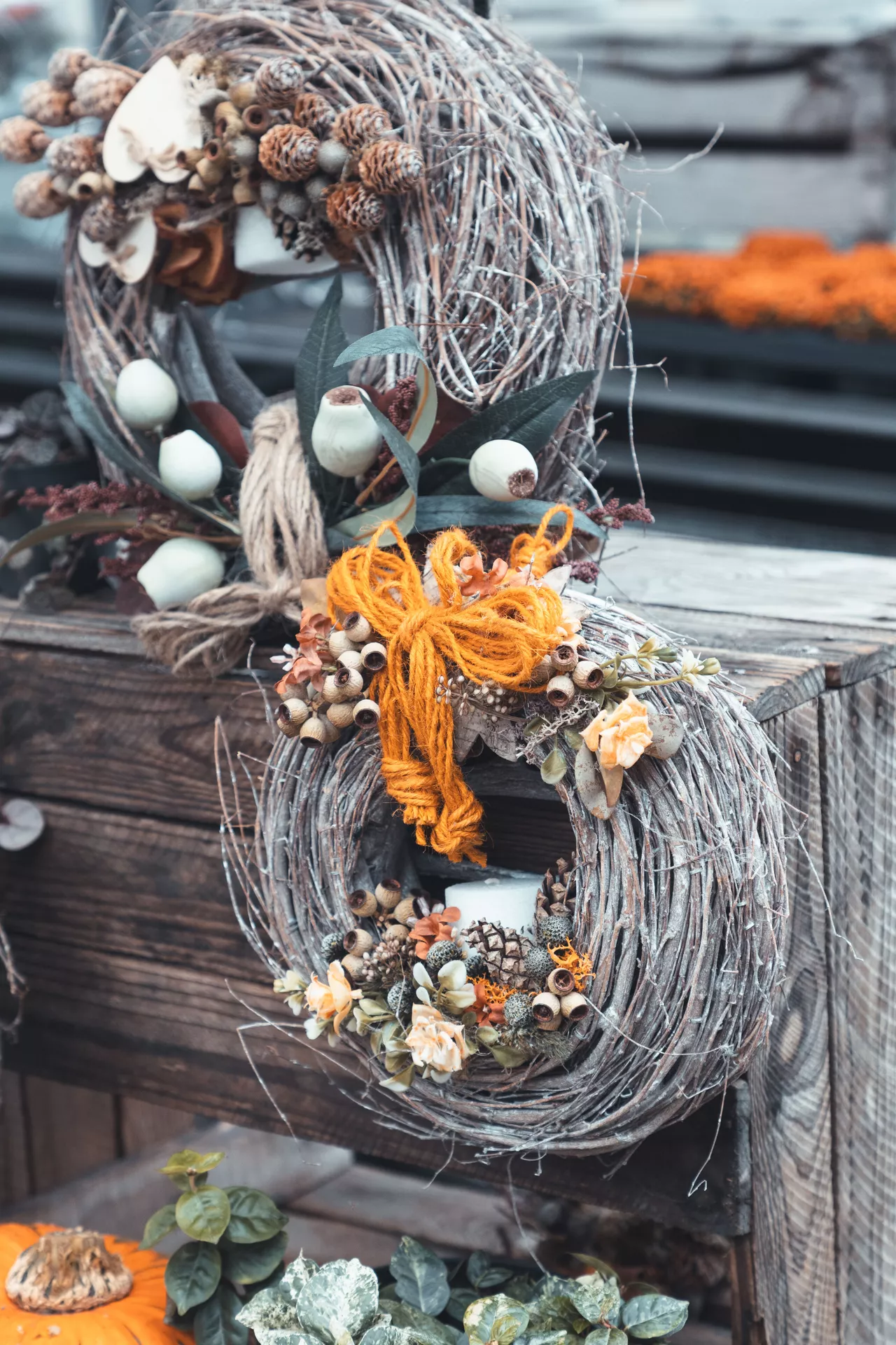 DIY autumn craft ideas featuring Creating A Willow Wreath with woven branches, dried flowers, seed pods, greenery, pinecones, and rustic orange yarn for a cozy handmade fall decoration.