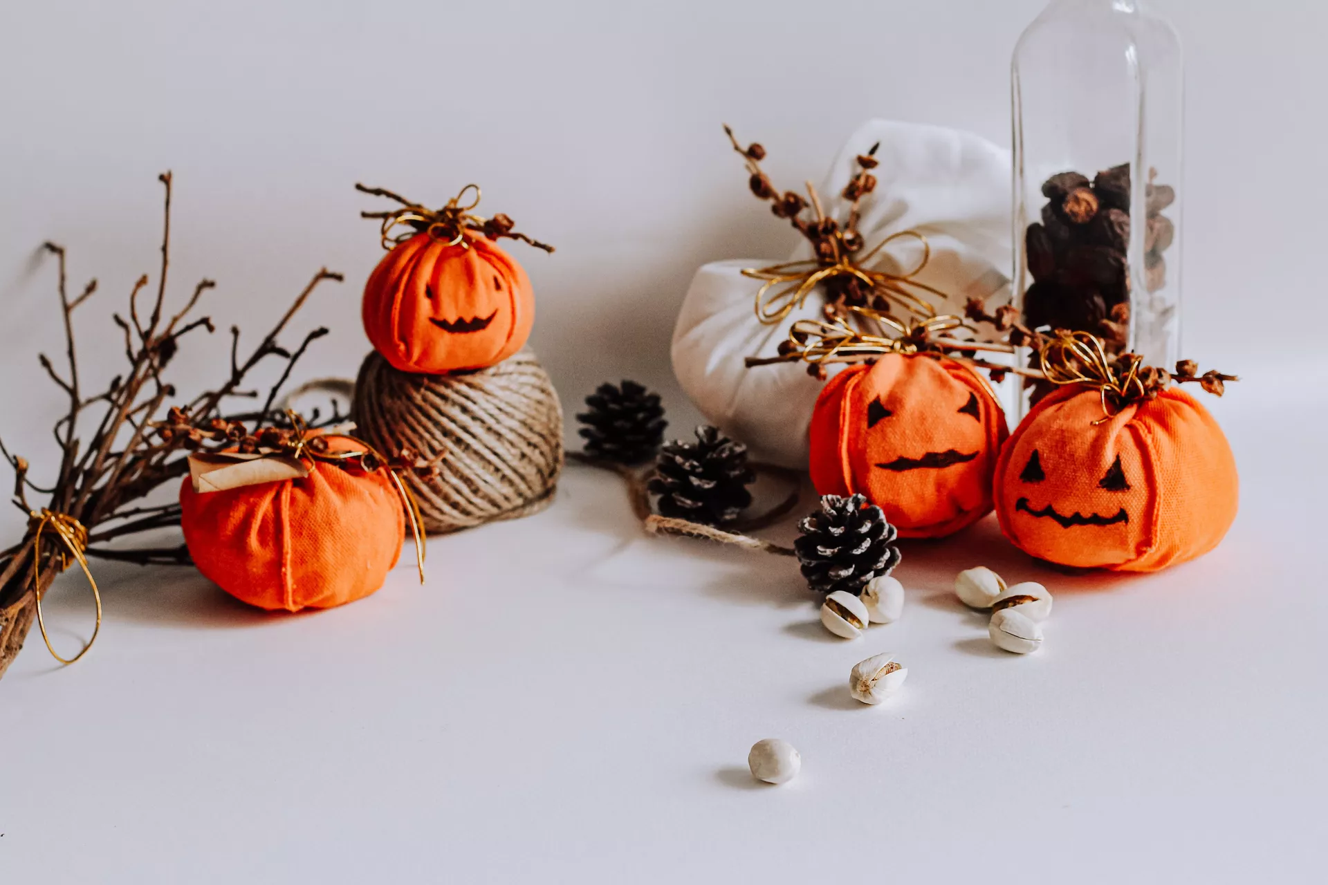 DIY autumn craft ideas featuring Making Pumpkins Out Of Small Fabric Bags, with cute orange fabric pumpkins decorated with hand-drawn faces, twigs, and gold bows, surrounded by pinecones and rustic fall decorations.