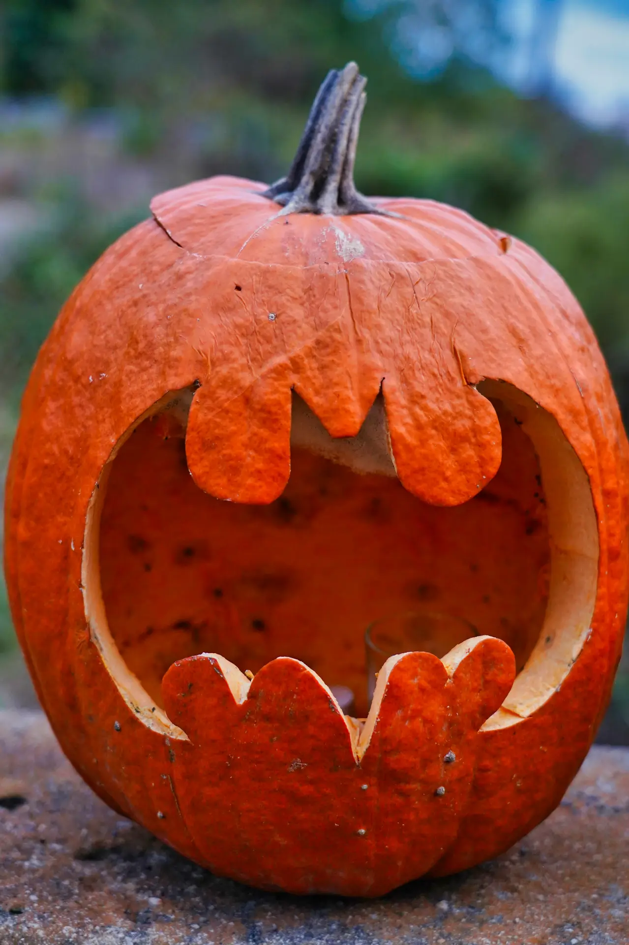 Pumpkin carving ideas featuring a bat-inspired jack-o-lantern with a large open mouth and jagged carved teeth, creating a simple and spooky Halloween decoration.