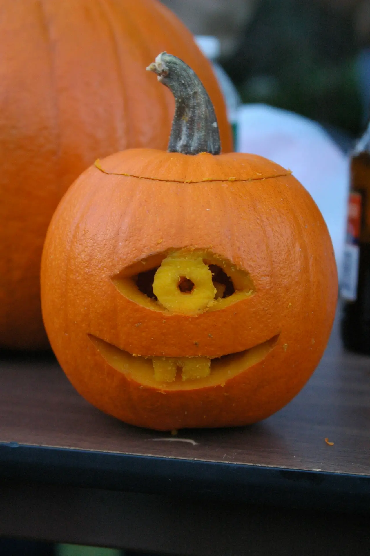 Pumpkin carving ideas featuring a playful cyclops face with one large carved eye, a round pupil, and a wide smiling mouth with two square teeth.